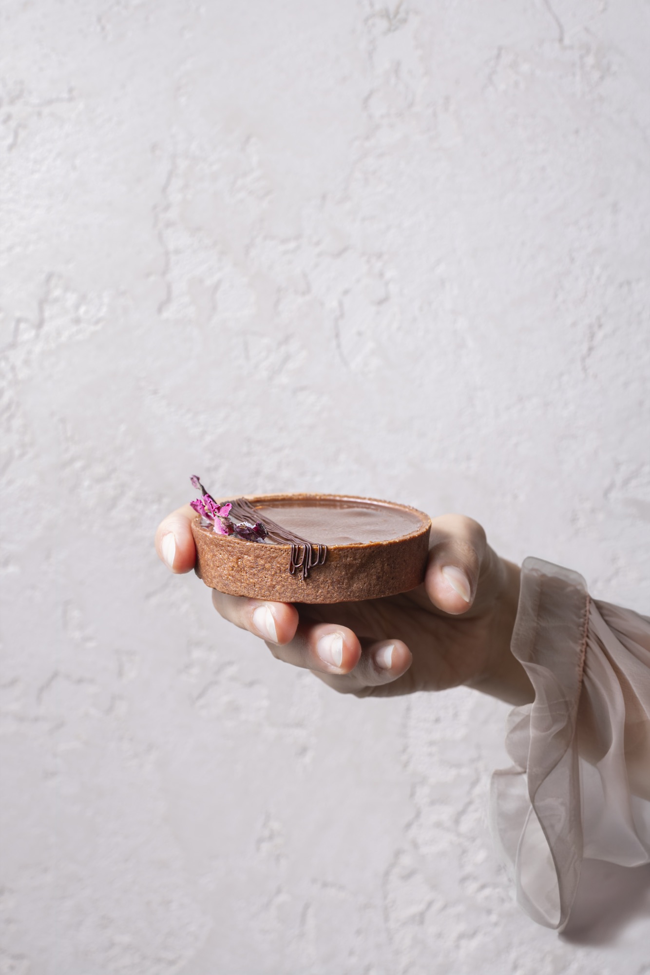 Hand holding individual chocolate caramel tart