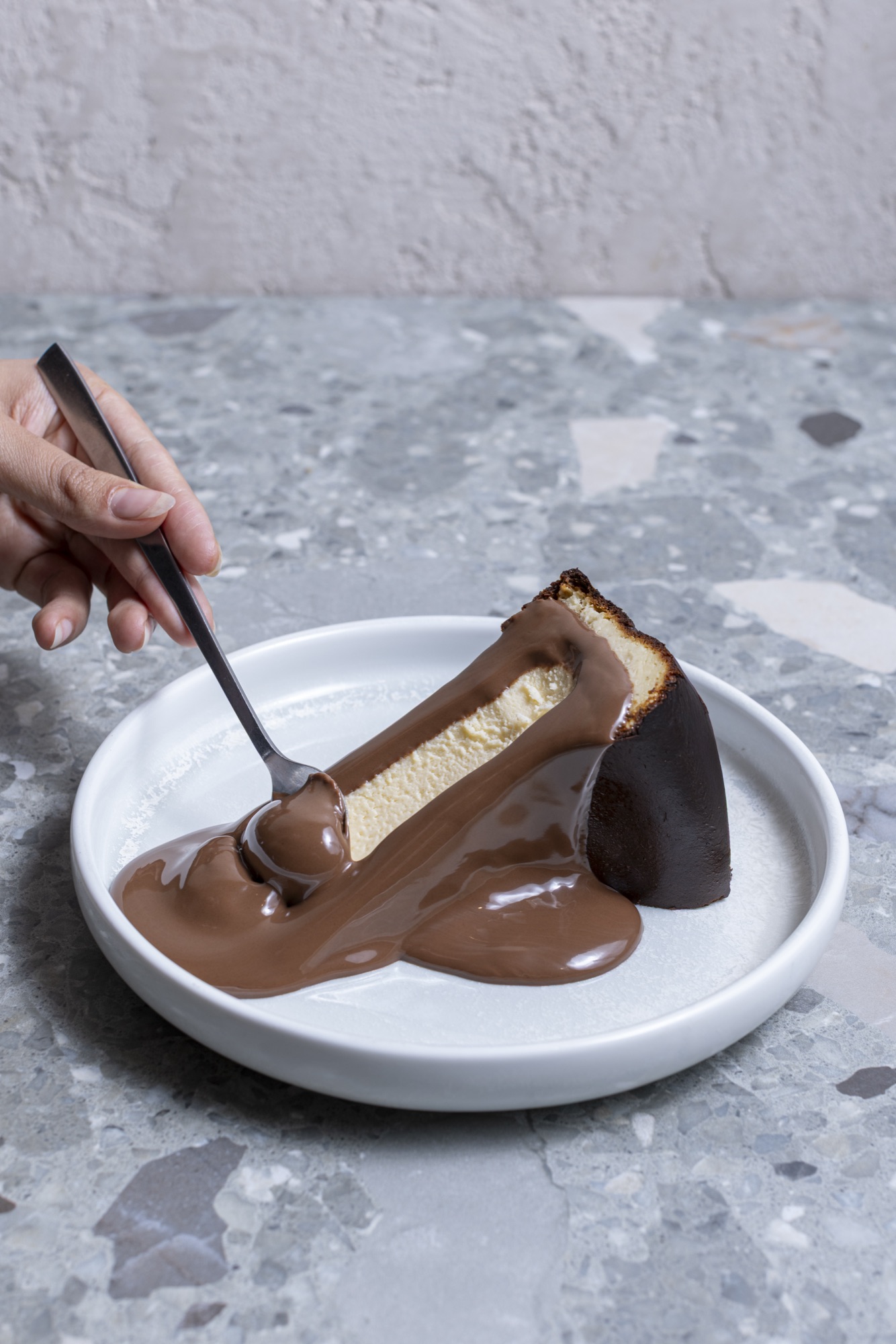 Cheesecake slice lifted with chocolate sauce dripping